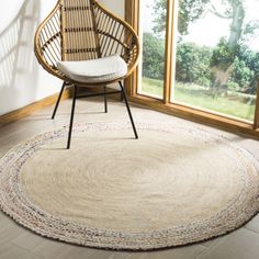 a chair sitting in front of a window next to a large rug on the floor