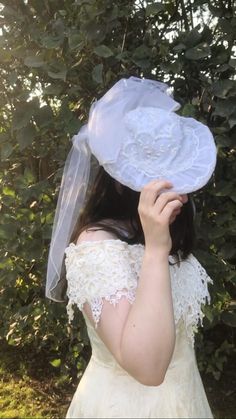 a woman wearing a veil and holding a white hat