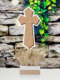 a paper cut out of a cross on top of a table next to a stone wall