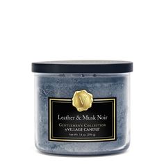 a candle that is blue and has a gold emblem on the front, with a black lid