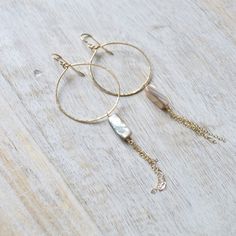 Gold filled hammered hoops feature creamy beige colored mother of pearl shells with dangling gold chains. Bohemian Gold Hoop Earrings With Dangling Charms, Bohemian Gold Mother Of Pearl Earrings, Beige Dangle Jewelry With Ear Wire, Metal Dangle Hoop Earrings With Pearl Charm, Pearl Charm Dangle Hoop Earrings, Gold Bohemian Dangle Pearl Earrings, Bohemian Gold Dangle Pearl Earrings, Beachy Earrings, Earrings Gold Hoop