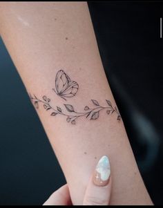 a woman's arm with a butterfly and leaves tattoo on the left side of her arm