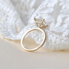 a diamond ring sitting on top of a white blanket next to a knitted cloth