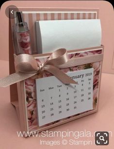 a pink and white box with a calendar on the front, ribbon tied around it