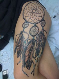 a woman's thigh with a tattoo on it that has an image of a dream catcher