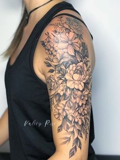 a woman's arm with flowers and leaves on it