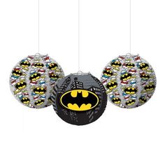 three batman ornaments hanging from strings on a white background with black and yellow designs in the shape of balls