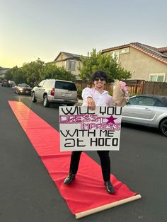 a woman standing on top of a red carpet holding a sign