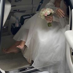 a bride sitting in the back seat of a car with her feet on the floor