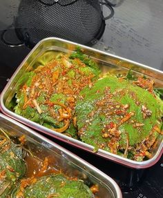 two metal pans filled with food sitting on top of a stove next to each other