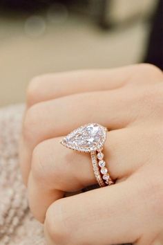 a woman's hand with a diamond ring on top of her finger and an engagement band