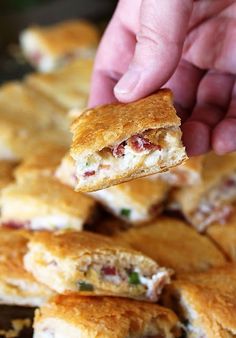 a person is picking up some food from a pile on a tray with other pastries