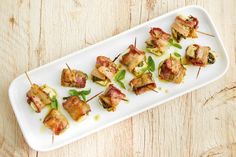 small appetizers are arranged on a white platter with toothpicks and garnishes