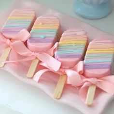 there are four popsicles with pastel icing on them and pink bows around the edges