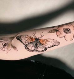 a woman's arm with a butterfly and flowers on it