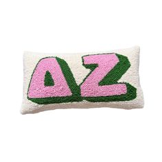 a pink and green embroidered pillow with the word az in large letters on it's side