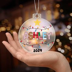 a hand holding a glass ornament with the word ehley on it's side