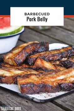 barbecued pork belly on a plate with watermelon in the background