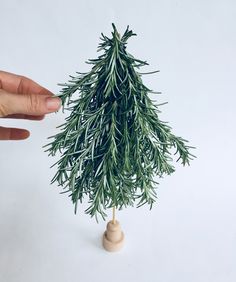 someone is holding a fake christmas tree in their hand