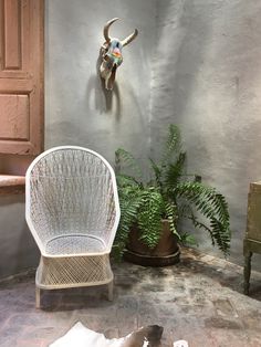 a white chair sitting next to a potted plant on top of a stone floor