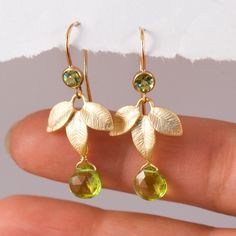 "Dainty Peridot Earrings Gold, Mother of the Bride Earrings, August Birthday Gift, Elegant Leaf Dangle, Meaningful Jewelry Gift, Birthstones Simple and elegant, these earrings feature a tiny birthstone wire wrapped onto a stunning gold or silver plated leaf charm with a matching stone on top. Available in 6 different stone & color options, these earrings make ideal gifts! H O W ∙ T O ∙ O R D E R 1st DROP DOWN menu * Select which of the stones you would like on your necklace (See listing phot Green Drop Earrings For Birthday, Gold Party Earrings With Birthstone, Formal Peridot Drop Earrings, Green Leaf-shaped Party Jewelry, Elegant Peridot Earrings For May Birthstone, Peridot Dangle Jewelry For Gift, Peridot Dangle Earrings For May Birthstone, Mother Of The Bride Earrings, Peridot Gemstone Dangle Earrings