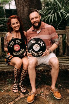 a man and woman sitting on a bench holding up record records that say be the record