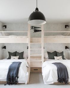 two bunk beds in a room with white walls and carpeted flooring, one has a ladder to the ceiling