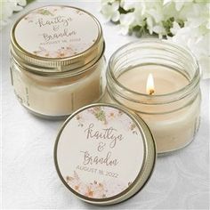 two small jars filled with candles sitting on top of a white table covered in flowers