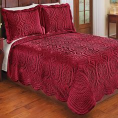 a bed with red comforter and pillows in a room