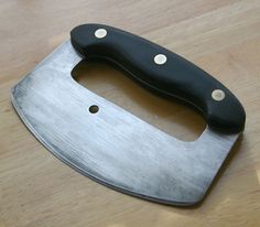 a knife on a wooden table with a black handle and two holes in the blade