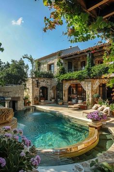 an outdoor swimming pool surrounded by greenery and stone walls, next to a house