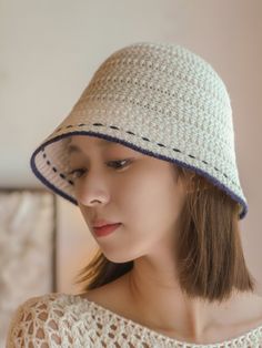 a woman wearing a white crochet hat with a blue stripe on the brim