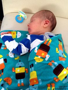 a baby is sleeping on a bed with a blue blanket and toy in his hand