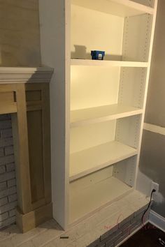 an empty white book shelf in the corner of a room with no one around it