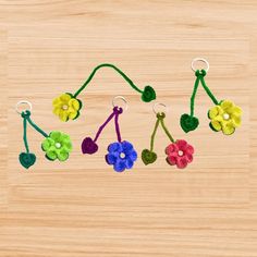 several colorful flowers are hanging on a wooden surface with metal hooks and string attached to them