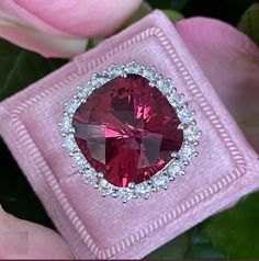 a close up of a ring with a red stone in it on a pink cloth