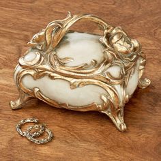 an ornate gold and white box sitting on top of a wooden table next to a chain