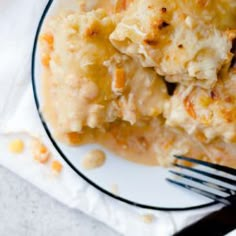 a white plate topped with macaroni and cheese casserole next to a fork