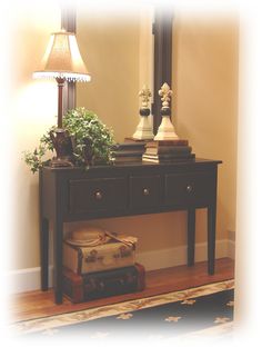 a wooden table topped with a mirror and a lamp next to a plant on top of a hard wood floor