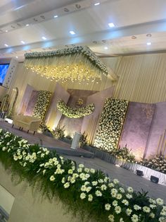 an indoor wedding setup with flowers and greenery on the wall, along with chandeliers