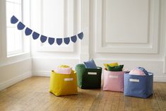 four different colored storage bins sitting on the floor in front of a white wall