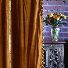 a vase filled with flowers sitting on top of a table next to a brick wall