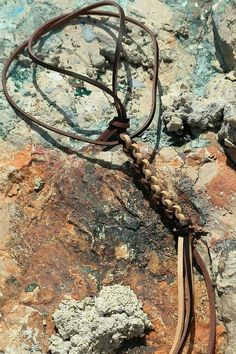 a brown leather cord is laying on some rocks