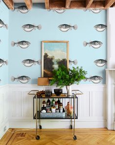 a bar cart with drinks on it in front of a wallpapered background that looks like fish