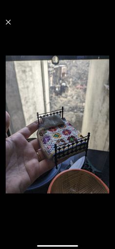 someone is holding a miniature piece of art in their hand, with the view of a city below