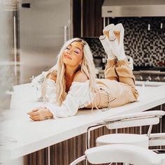 a woman laying on top of a counter in a kitchen