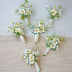 four bridal bouquets with daisies and greenery on the stems are laid out