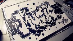 a notebook with graffiti written on it sitting on a desk next to markers and pens