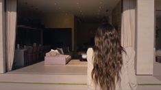 a woman with long hair standing in front of a living room