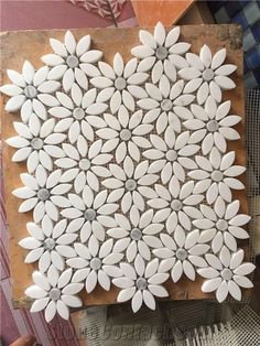 white flowers are arranged on top of a piece of wood, and placed in the shape of a flower